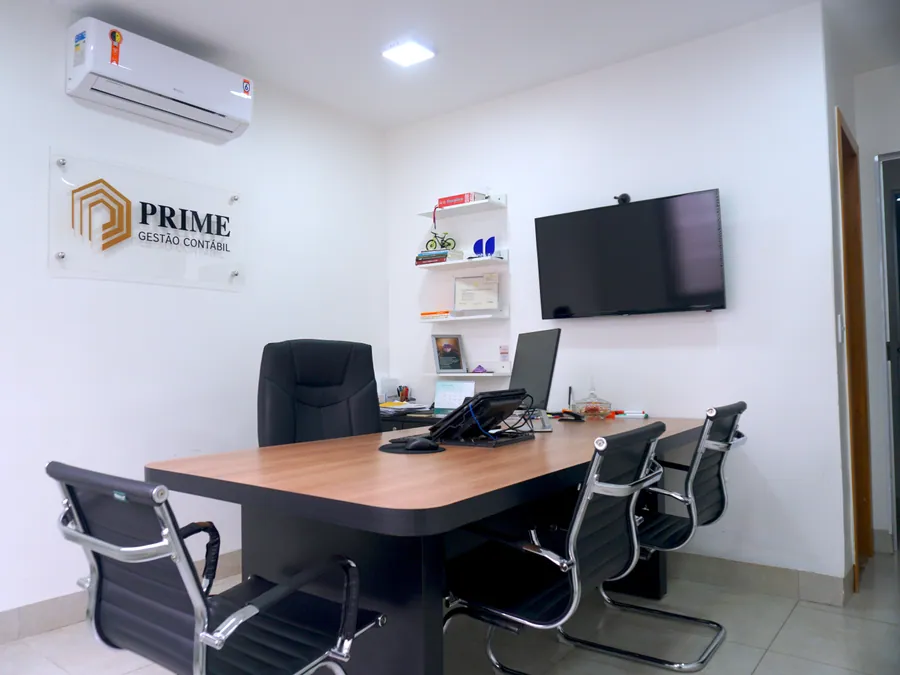 Sala de reunião do escritório, com mesa ampla e televisor para atendimentos